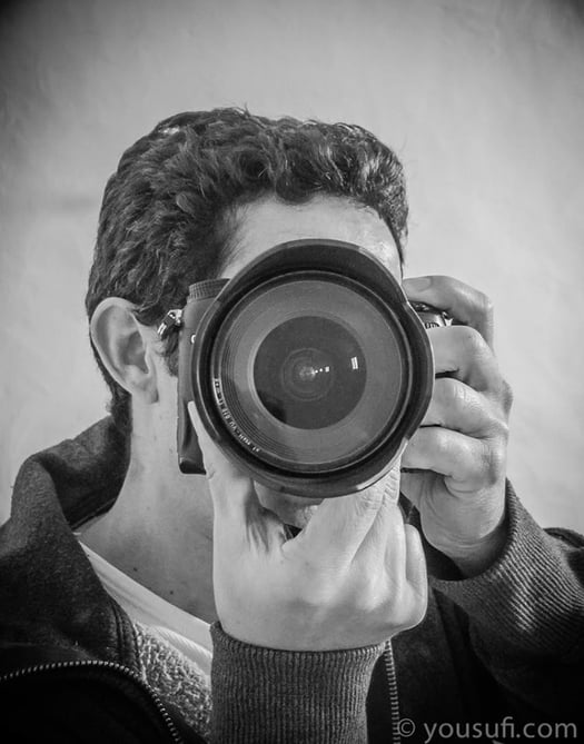 Artist Yous holding and pointing the dslr camera towards you