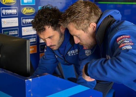 two men in blue jackets looking at data on a laptop