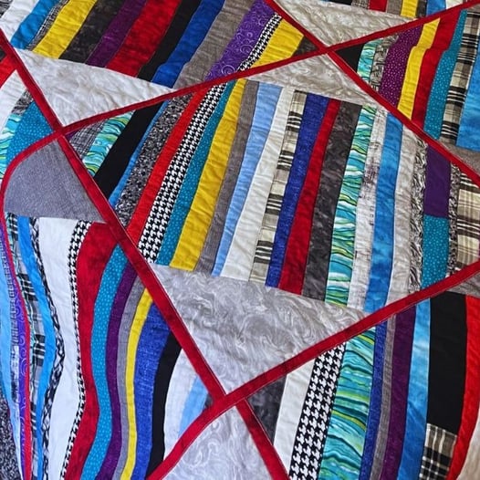 colorful quilt with red sashes and multicolored strips made for my son