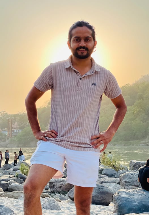 a man standing on a rocky beach with a sunset in the background