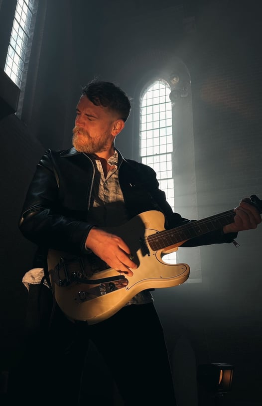 a man in a leather jacket playing guitar