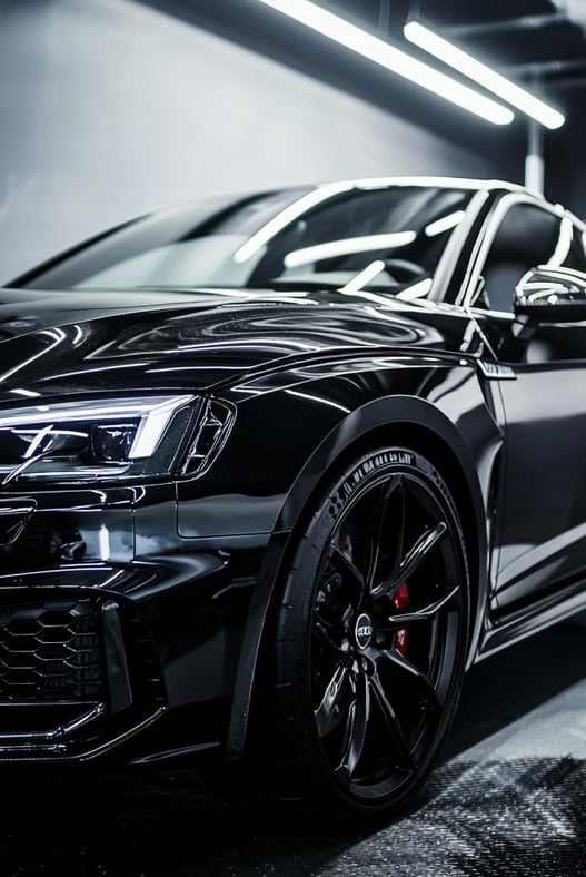 Véhicule Audi à la carrosserie noire brillante dans un garage éclairé aux néons