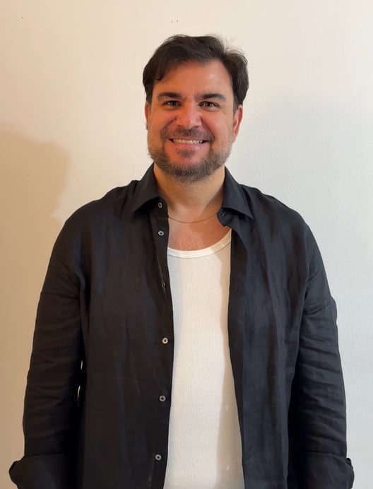 a man in a black shirt and jeans standing in front of a wall