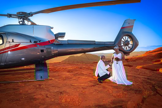 groom kneeling to bride by helicopter