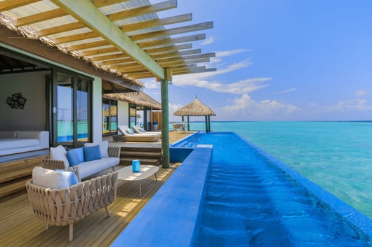 a large pool with a lounge chair and a couch from Velassaru Maldives