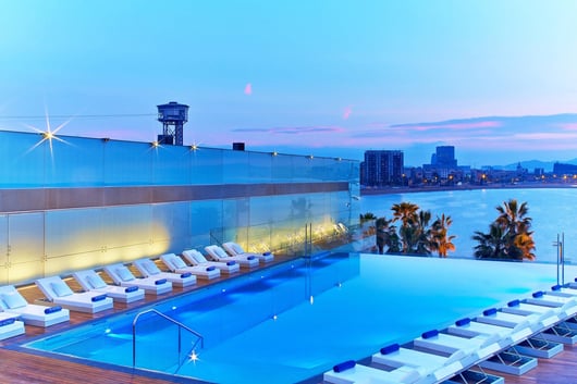 a pool with lounge chairs and a view of the city from W Barcelona hotel