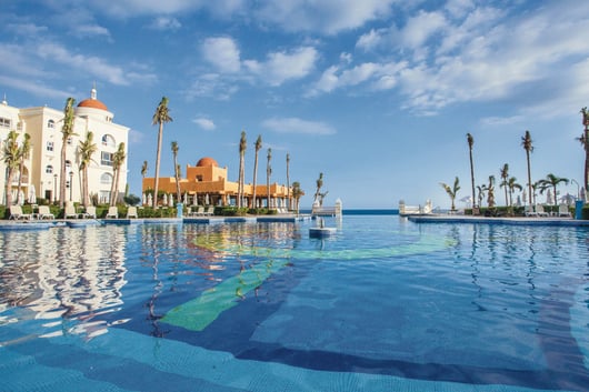 a pool with a view of the ocean from Riu Palace Cabo San Lucas