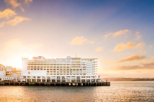 a large white building with a boat in the water from Hilton Auckland hotel