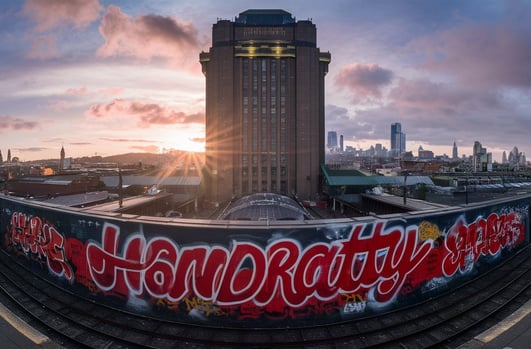 a train station with "HANDRATTY" graffiti on the side of the tracks