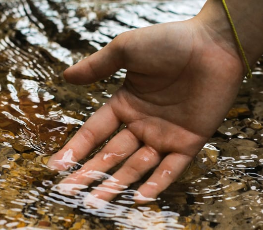 Main dans l’eau claire symbolisant l’apaisement mental et la lecture subtile du champ énergétique