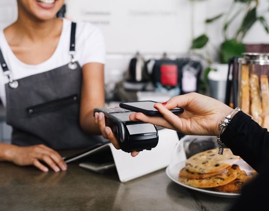 A customer pays using her phone connecting to a wireless point of sale terminal.