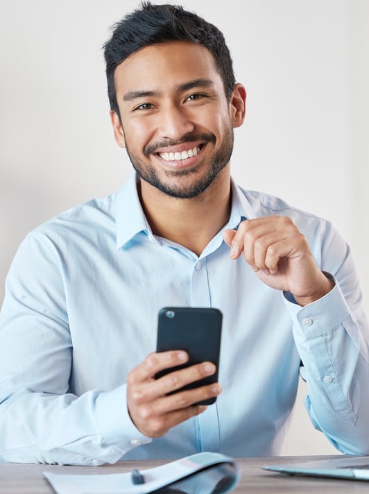 a man sitting at a desk with a cell phone in his hand