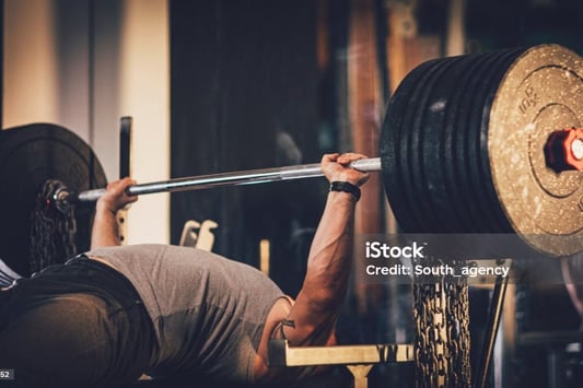 a man doing a barbell bench press in a gym