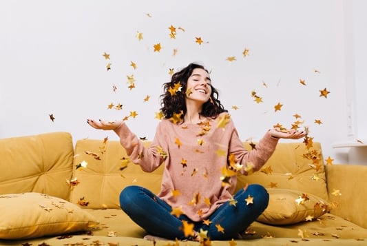 a woman sitting on a couch with her hands up and holding her hands out to