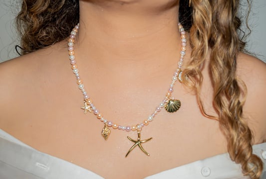 a woman wearing a white dress and a necklace with a starfish
