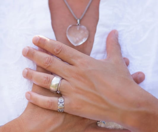 lady's hands clasped over her chest in a peaceful way she wears a white blouse and jewellry