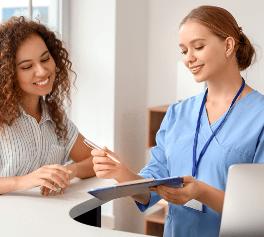 Dental practice front desk with a healthcare administrator and a patient.