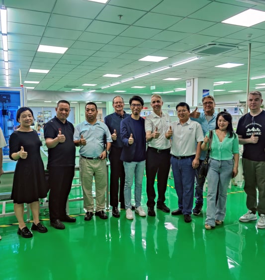 a group of people standing in a factory with thumbs up