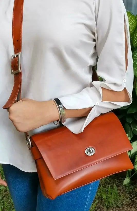 a woman in a white shirt and jeans jeans and a brown purse