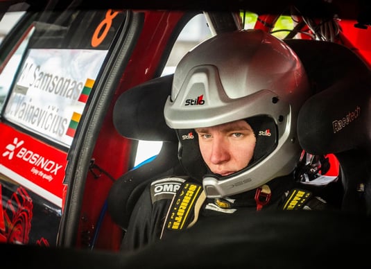 focused codriver with a helmet siting in a rally car and preparing for a stage start