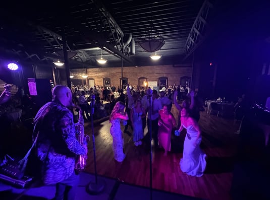 LuxeBand singer playing saxophone on stage for a crowd at a wedding