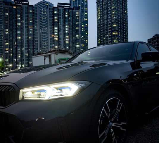 a black bmw car parked in front of a cityscapeople