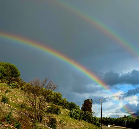 A double rainbow over a hill.