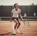 A young tennis player in sports attire is at a tennis court with their coach.