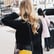 A woman with long blonde hair wearing a black coat walking outside