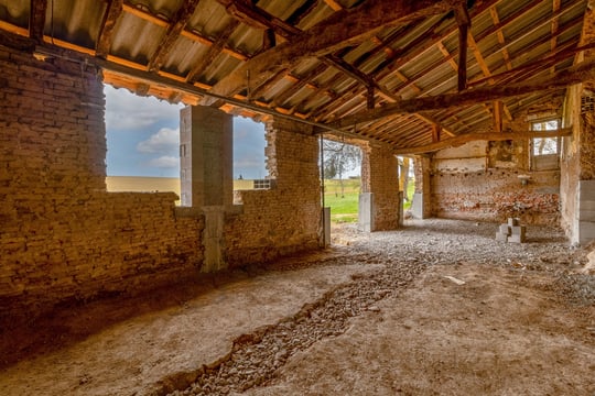 Ancienne grange en rénovation, sol décaissement et charpente visible, photo de suivi de chantier