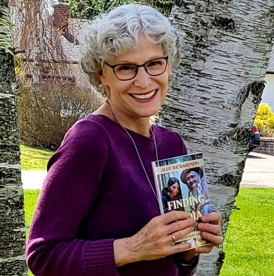 Allie Richardson author of Finding Lydia in a purple sweater holding her book
