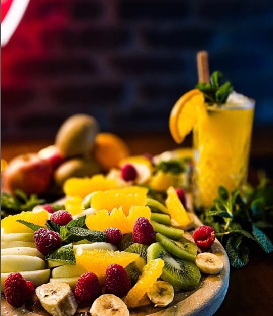 a plate of fruit and a glass of juice