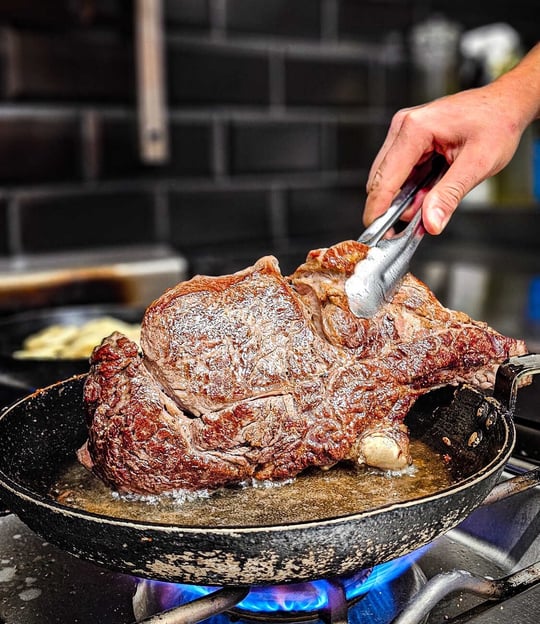 a person is cooking a steak steak on a pan