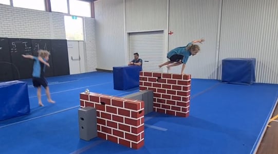 a person jumping over a brick wall