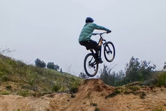 Mountain biker leaning too far back off the takeoff, front wheel rising too high