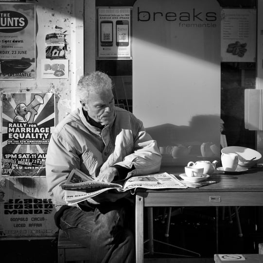 The street photography of Peter Pickering captures man reading the newspaper at a cafe