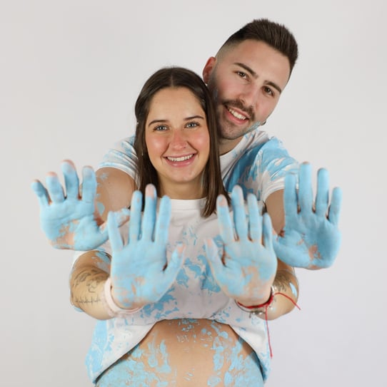 Sessió de fotos de gender reveal a Girona d'una parella amb pintura blava en estudi fotogràfic