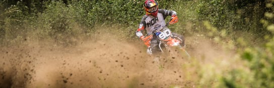 Motociclista su cross arancione e nera con numero 90 con fango