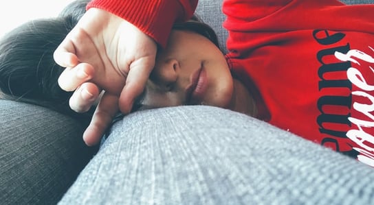 a woman is laying on a couch with her hands on her head