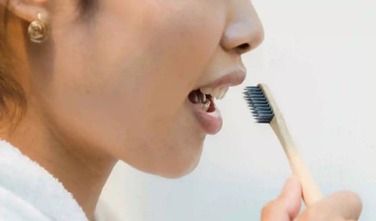 a woman in a bathrobear with a toothbrush in her mouth