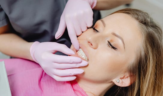 a woman is getting her teeth brushed with a dental mirror