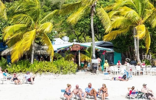 Guests sitting in beach chairs on the white sands outside The Soggy Dollar in BVI
