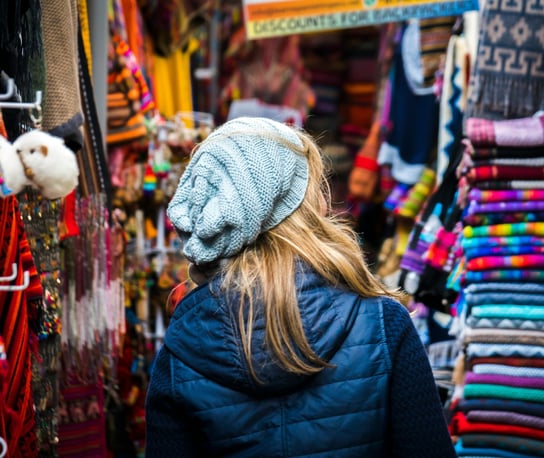 a woman in a blue jacket in a colorful market in Cusco Peru