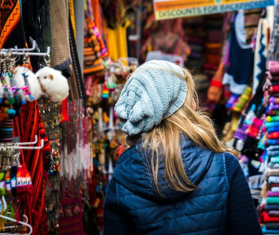 a woman in a blue jacket in a colorful market in Cusco Peru