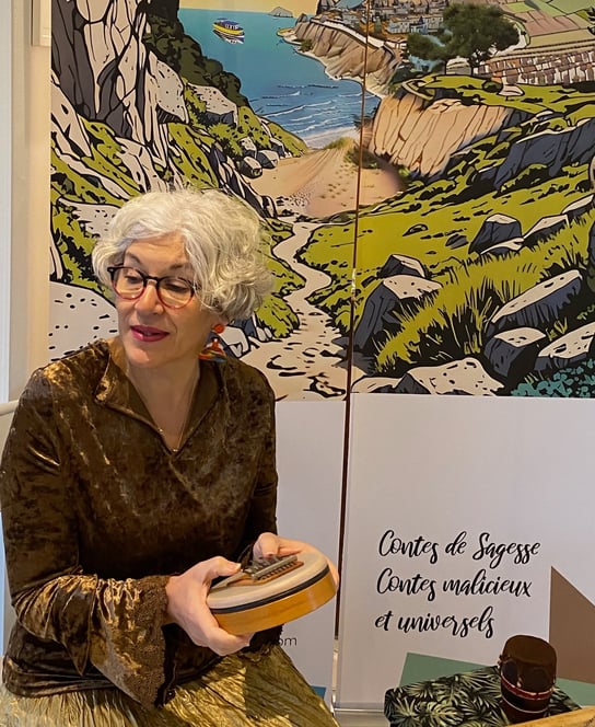La conteuse Jo Daltea devant son décor représentant un village posé sur une falaise