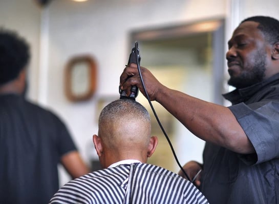 a man is getting his hair cut by a barber