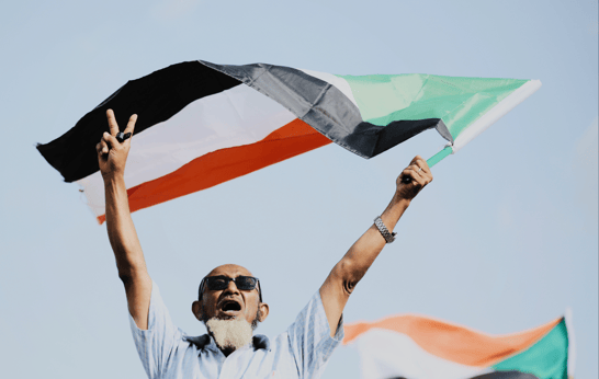 The Sounds of Sudan - cover image of a man holding the Sudanese flag