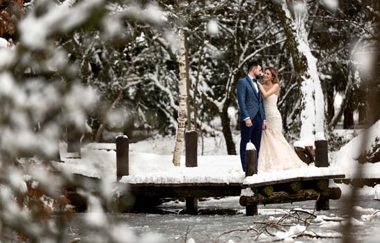 a bride and groom standing on a bridge over a river