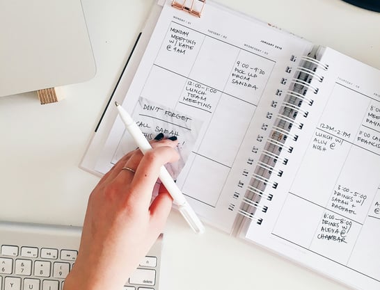 a person holding a pen and writing on a notebook