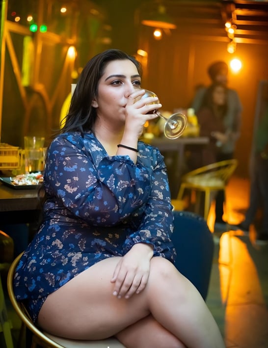 a woman sitting on a chair drinking a glass of wine